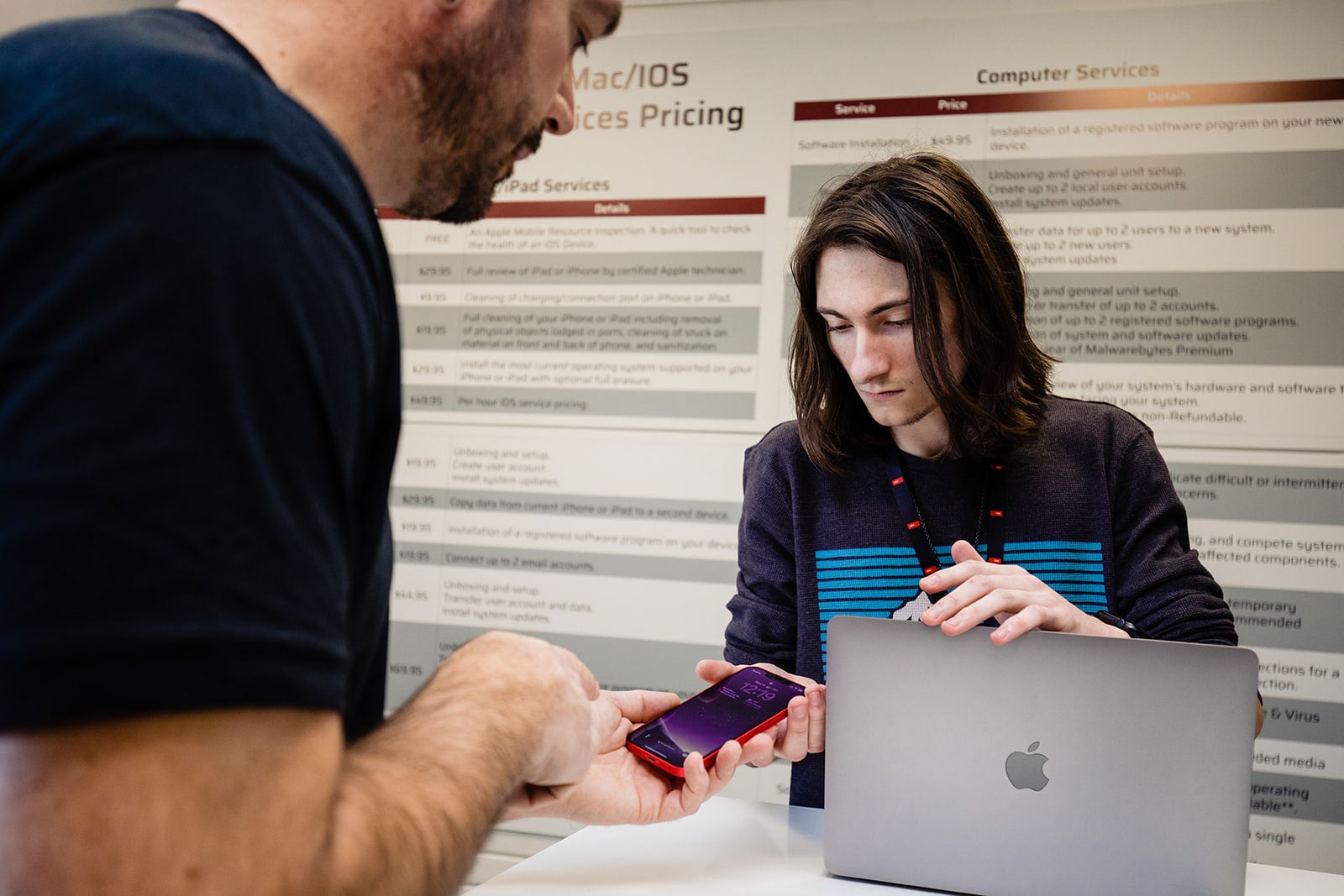A service representative helps a customer with a problem he's having with his phone.