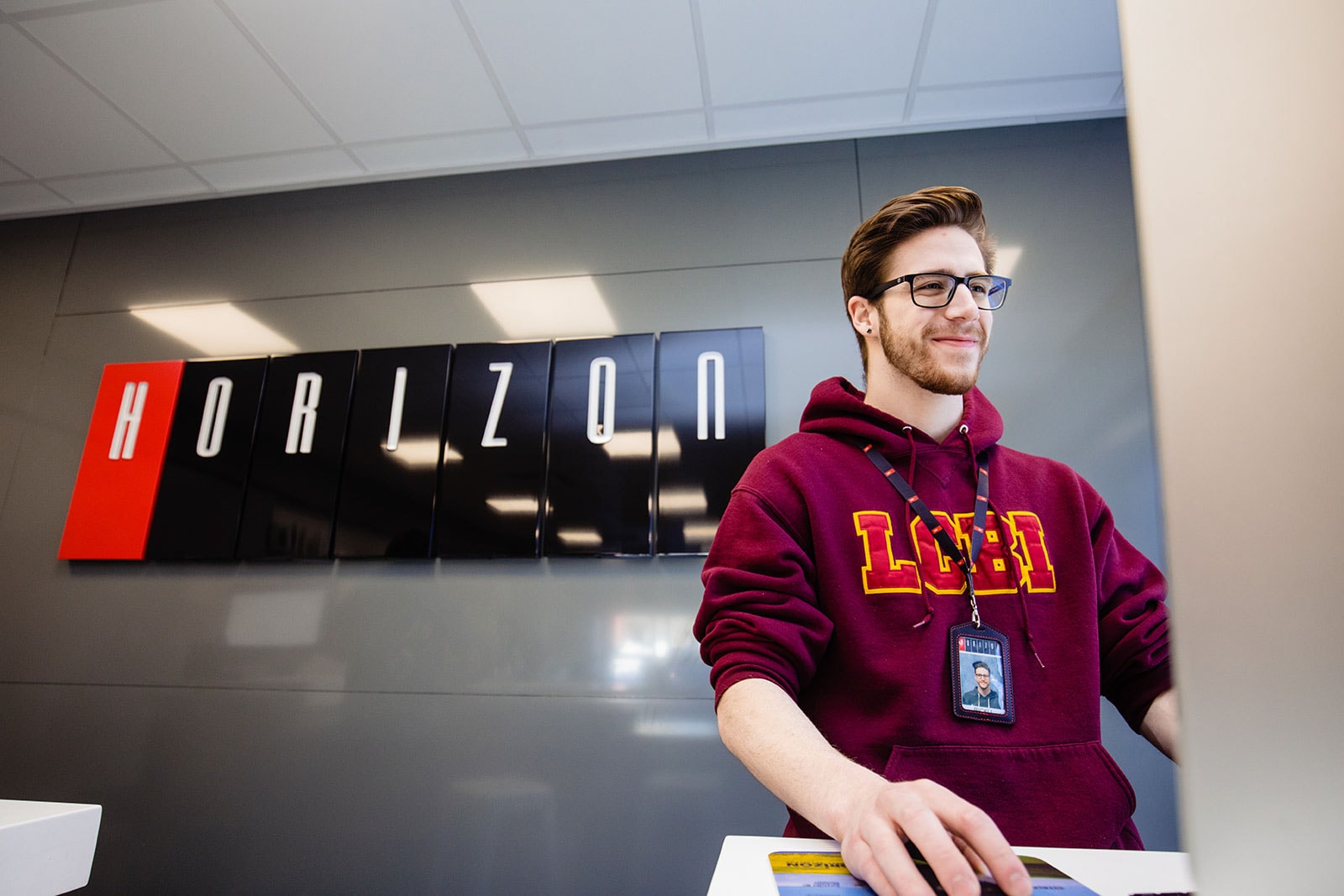 A customer service representatives stands at a kiosk with the Horizon Computer Solutions sign in the background.